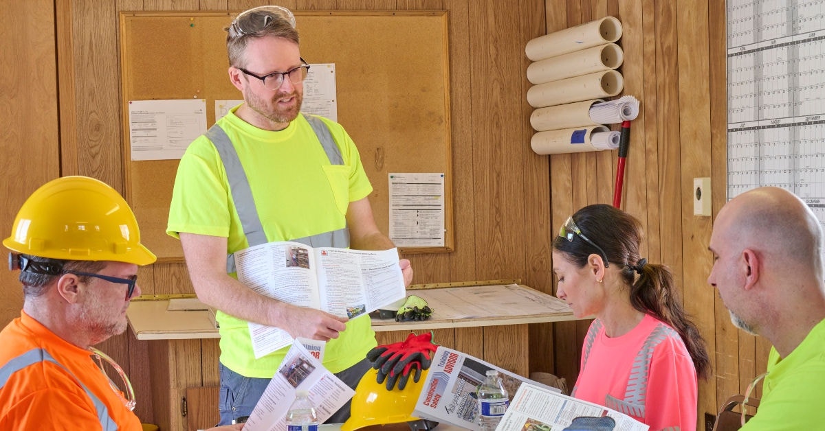 Construction manager leading an in‑person safety training session with employees in a classroom setting