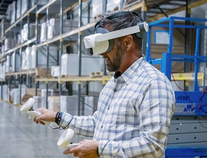 Male employee wearing a VR headset taking virtual reality training in a warehouse setting